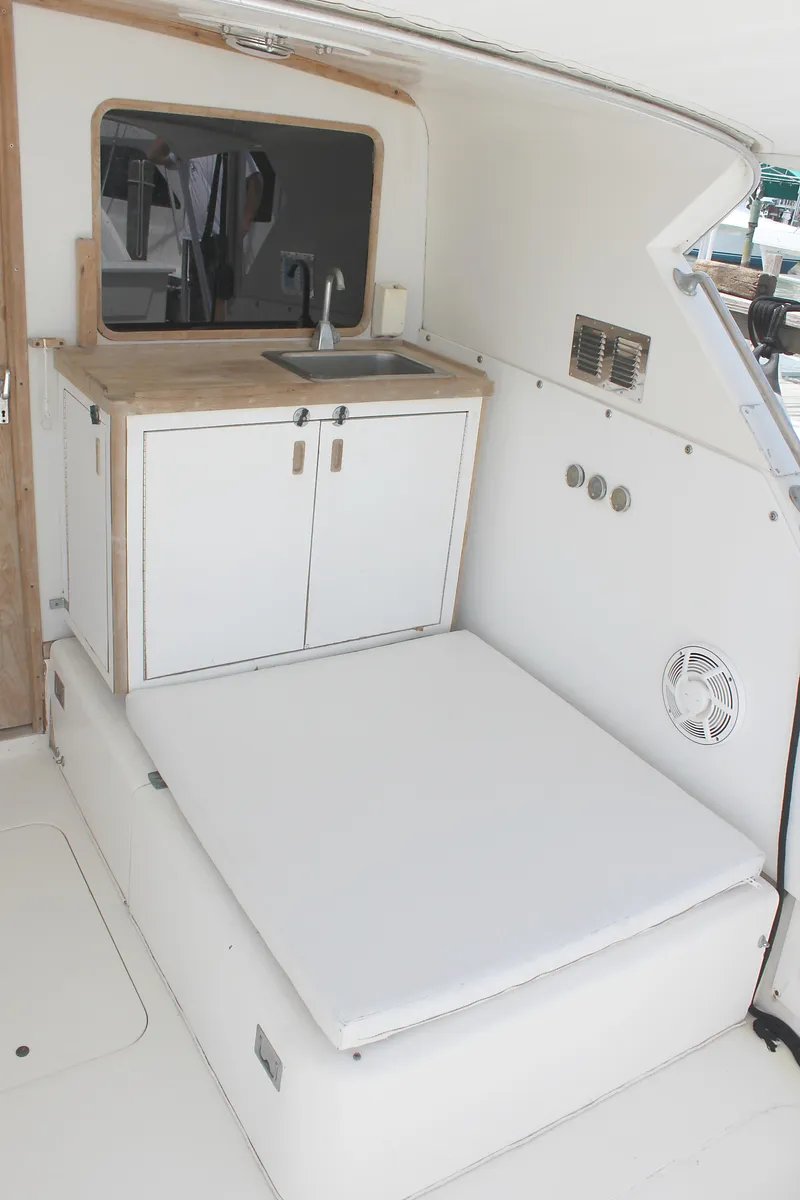 Slide: The Image of 1980 Bertram Sport Fisherman interior with sink and cushioned seating. - 12