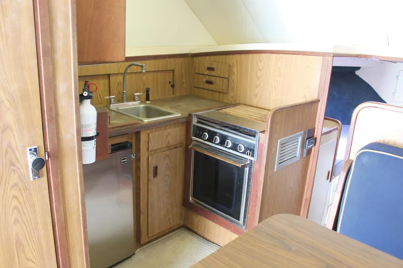 Slide: The Image of 1980 Bertram Sport Fisherman boat kitchen with sink, stove, and wooden cabinetry. - 19