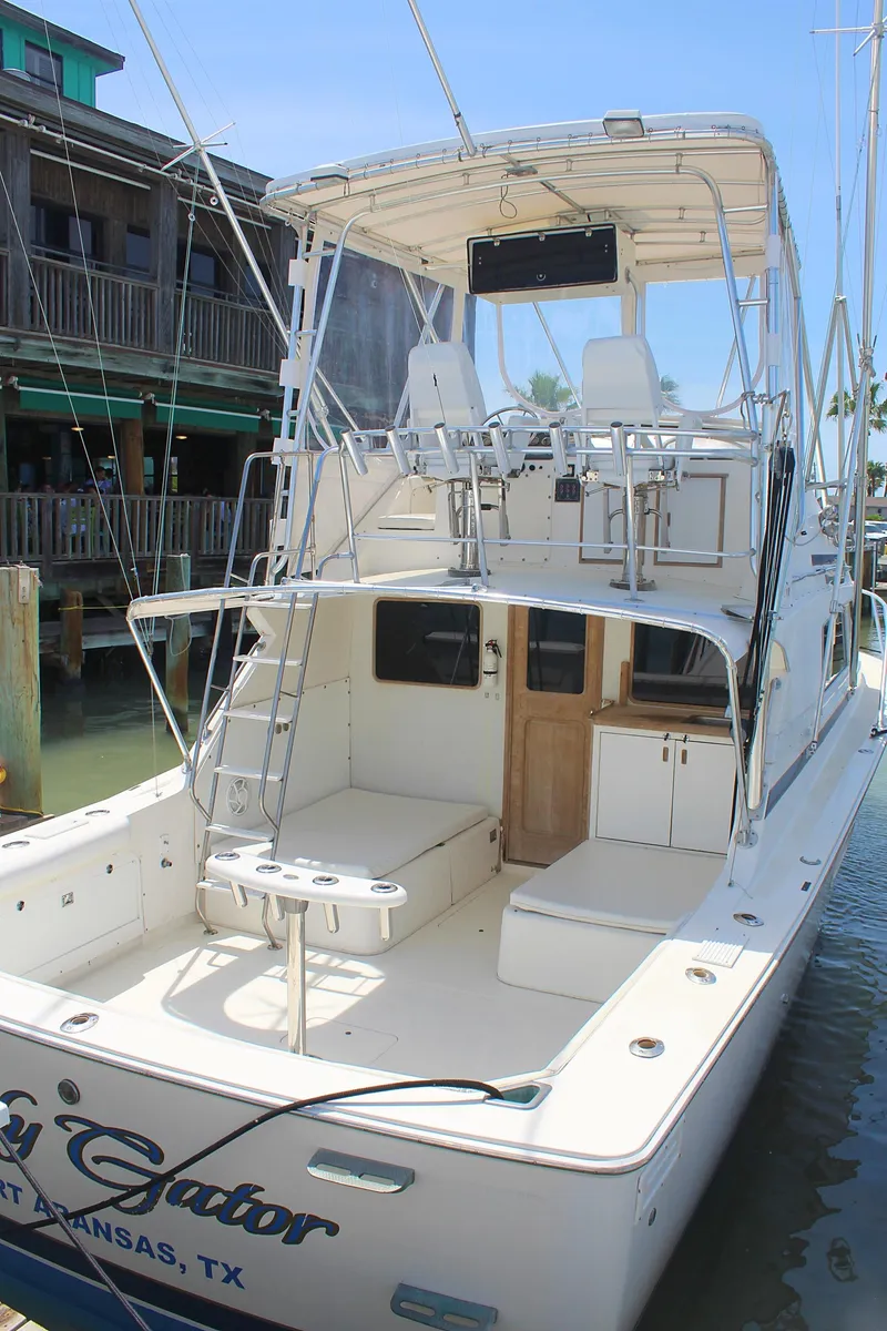 Slide: The Image of 1980 Bertram Sport Fisherman boat docked, featuring a spacious deck and upper helm station. - 4