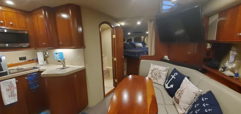 Slide: The Image of Interior of 2006 Cruisers Yachts 370 Express, featuring kitchen, seating area, and cozy cabin. - 11