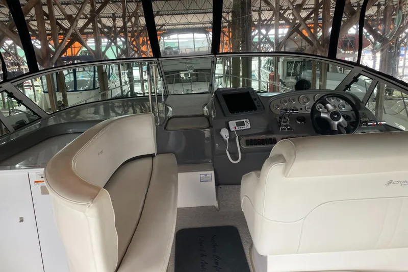 Slide: The Image of 2006 Cruisers Yachts 370 Express cockpit with steering wheel and seating in a marina setting. - 2