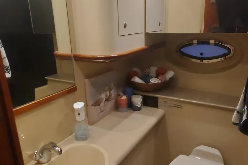 Slide: The Image of Bathroom interior of 2006 Cruisers Yachts 370 Express, featuring sink, mirror, and porthole window. - 22