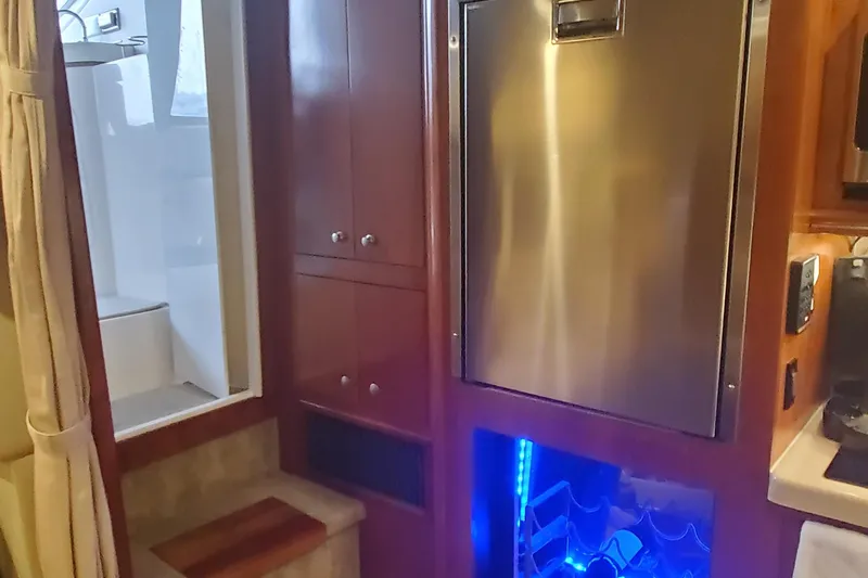 Slide: The Image of Interior of 2006 Cruisers Yachts 370 Express with stainless steel fridge and wooden cabinetry. - 27