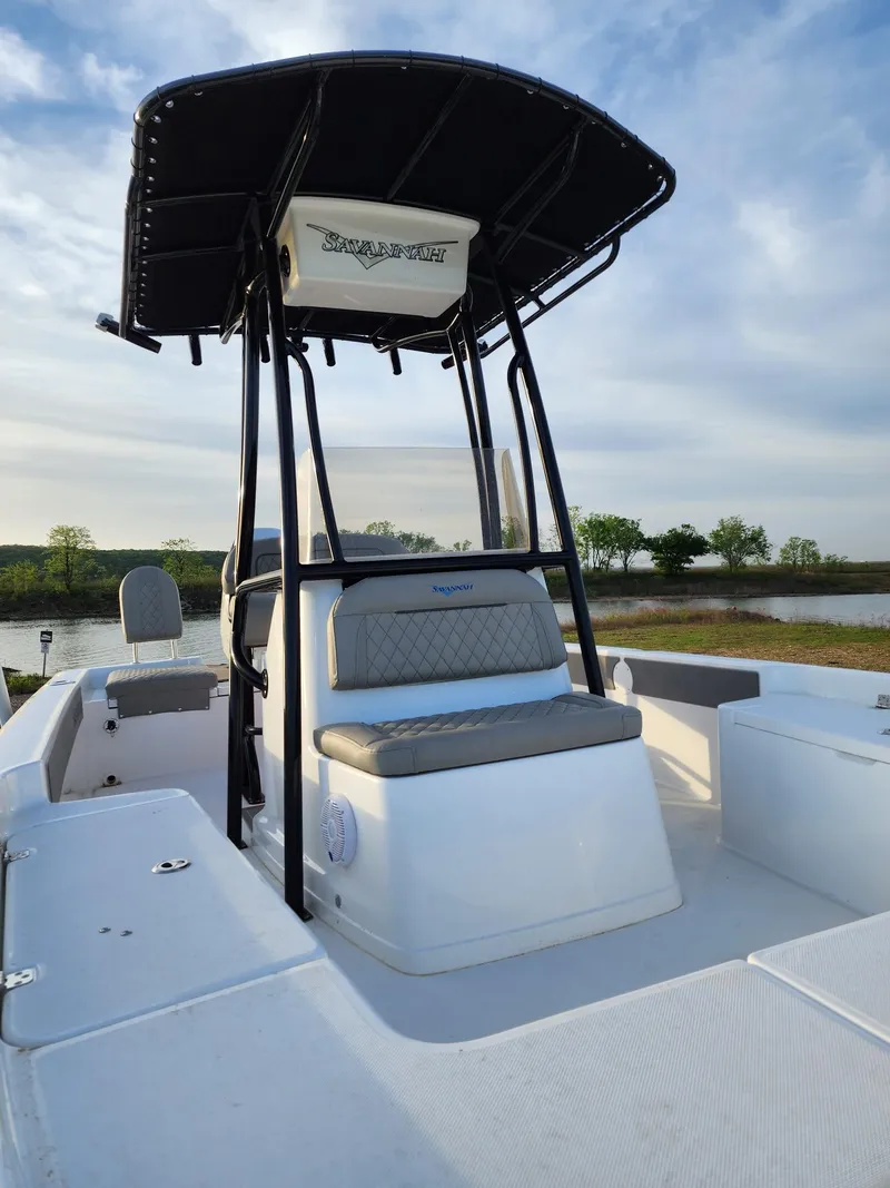 Slide: The Image of 2024 Savannah 210X boat with T-top and seating, docked by a serene lake. - 30