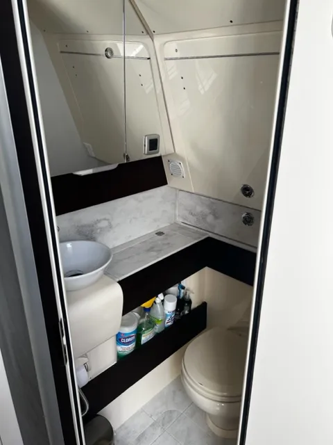 Slide: The Image of 2018 Scout 380 LXF boat bathroom with sink, toilet, and cleaning supplies. - 6