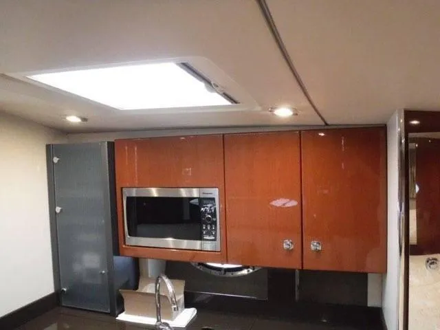 Slide: The Image of 2012 Formula 34 Cruiser kitchen with microwave, sink, and wooden cabinets. - 20