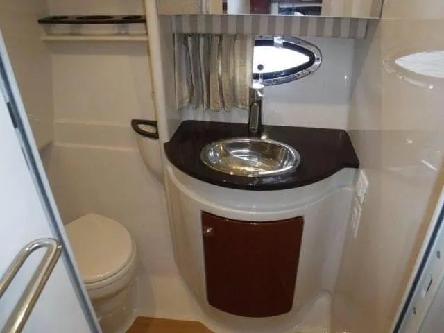 Slide: The Image of 2012 Formula 34 Cruiser bathroom with sink, toilet, and porthole window. - 27