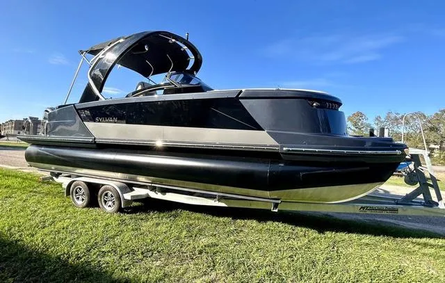 Slide: The Image of 2024 Sylvan M3 DLZ pontoon boat on a trailer under a clear blue sky. - 5