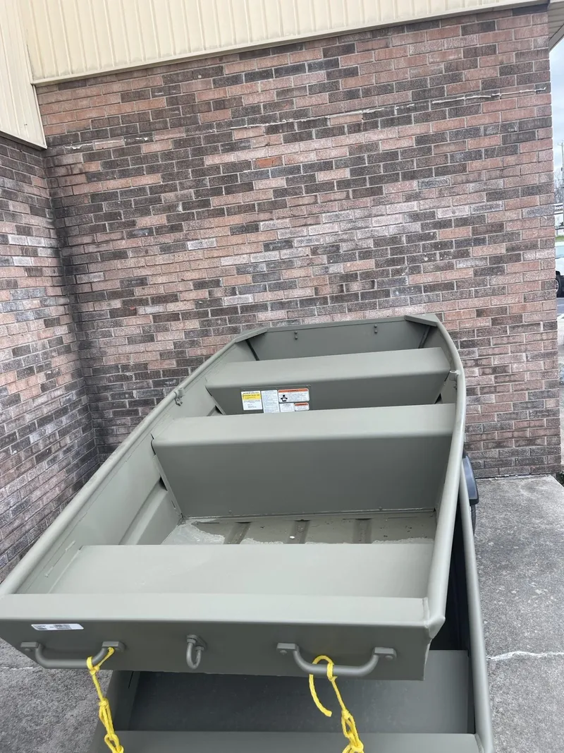 Slide: The Image of 2024 Tracker Grizzly 1036 Jon boat against brick wall, outdoor display. - 2