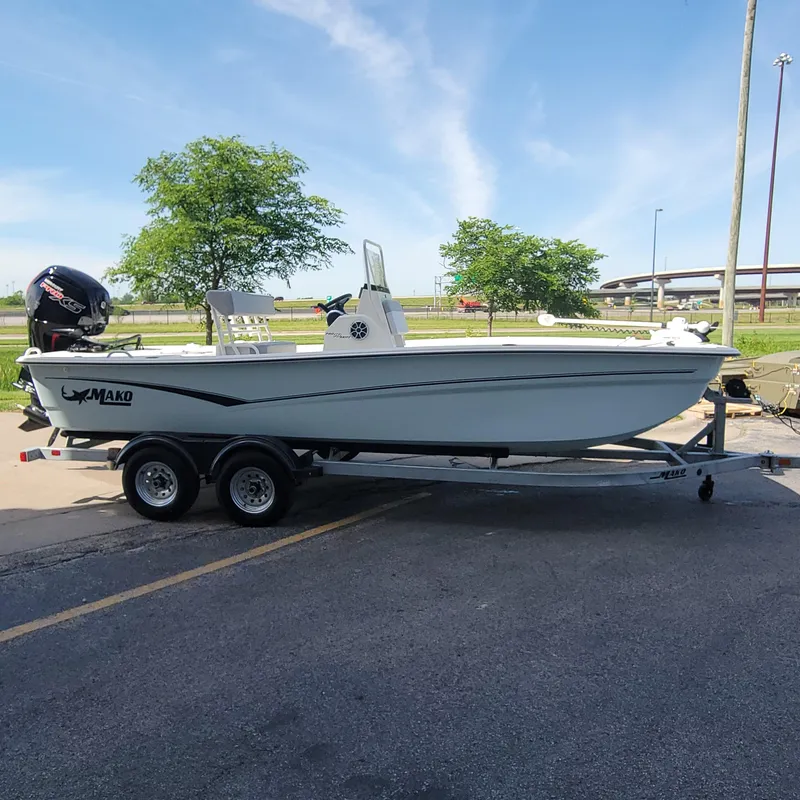 Slide: The Image of 2024 Mako Pro Skiff 19 CC boat on a trailer, parked outdoors. - 1