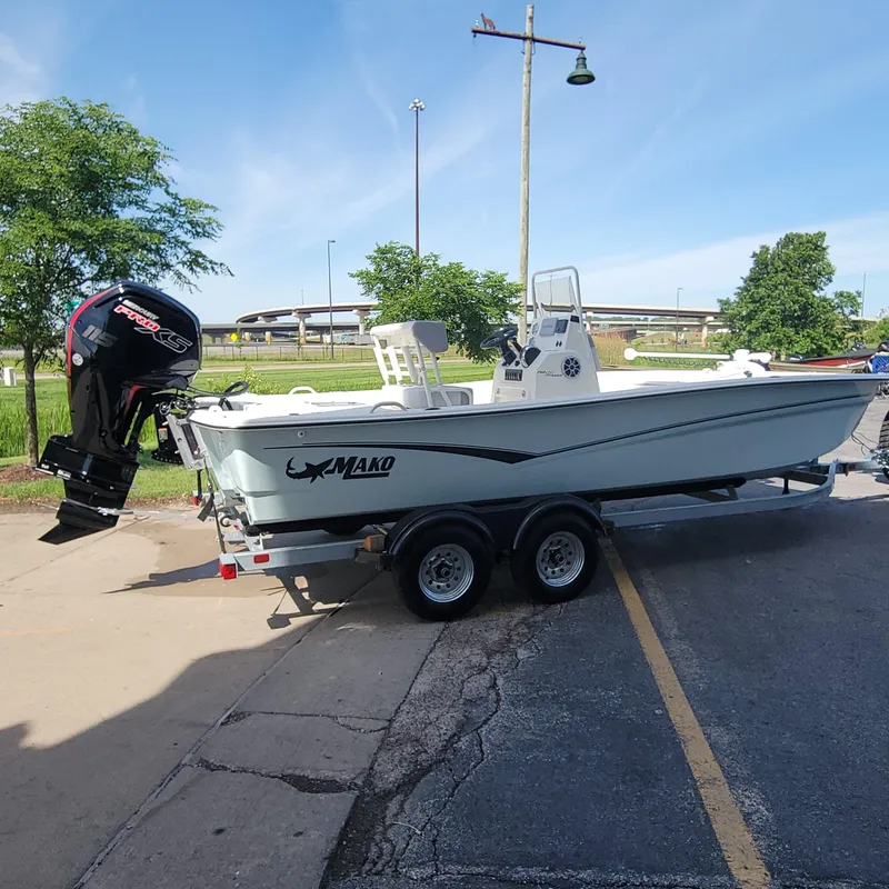 Slide: The Image of 2024 Mako Pro Skiff 19 CC boat on trailer with Mercury outboard motor. - 2
