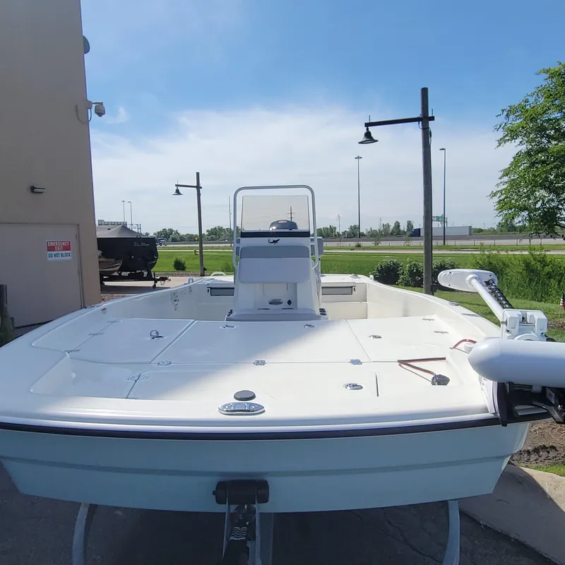 Slide: The Image of 2024 Mako Pro Skiff 19 CC boat displayed outdoors on a sunny day. - 4