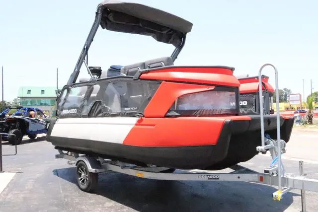 Slide: The Image of 2024 Sea-Doo Switch® Cruise 18 on trailer, red and black design, parked outdoors. - 8