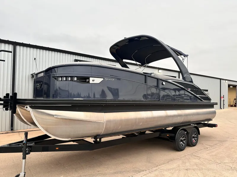 Slide: The Image of 2024 Bennington 23 RXSBA pontoon boat on trailer, parked outside a warehouse. - 2