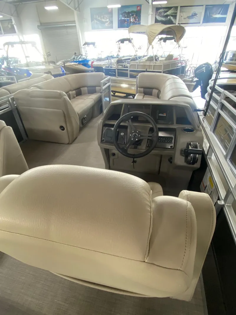 Slide: The Image of 2024 Sun Tracker Party Barge 20 DLX interior with beige seating and steering console. - 4