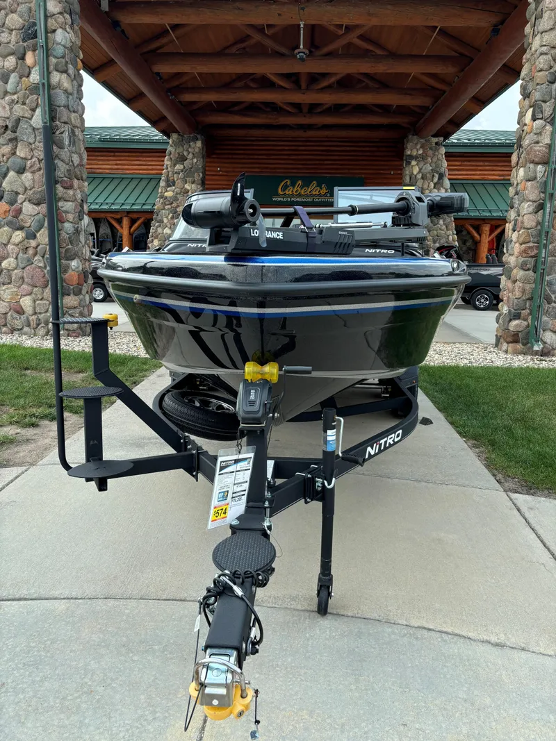 Slide: The Image of 2024 Nitro ZV19 Sport Pro boat on trailer outside a rustic building. - 2