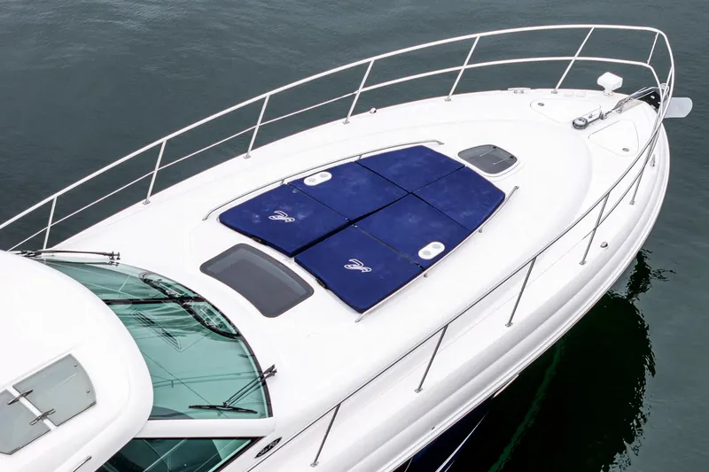 Slide: The Image of 2007 Sea Ray 48 Sundancer yacht with blue sun pads on deck, docked on calm water. - 10