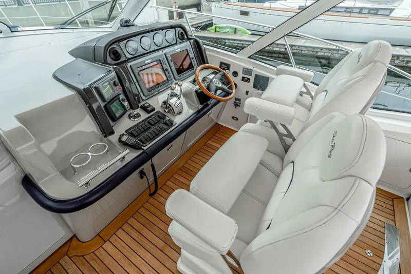 Slide: The Image of 2007 Sea Ray 48 Sundancer helm with dual seats, wooden steering wheel, and advanced navigation controls. - 24
