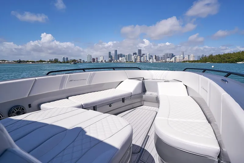 Slide: The Image of 2020 Midnight Express 37' Open boat with luxurious seating and city skyline in the background. - 8