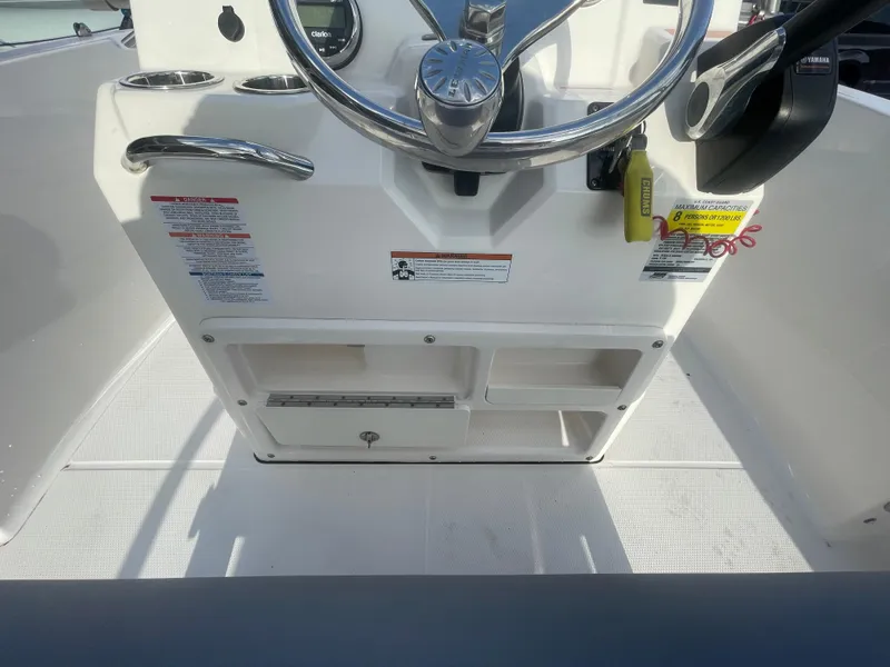 Slide: The Image of 2021 Robalo R180 Center Console boat helm with steering wheel and storage compartments. - 23