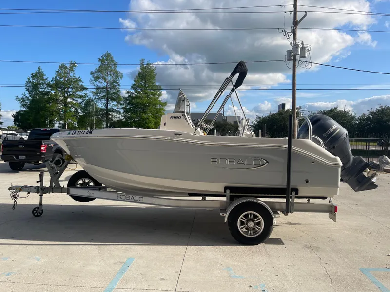 Slide: The Image of 2021 Robalo R180 Center Console boat on a trailer in a parking lot. - 4