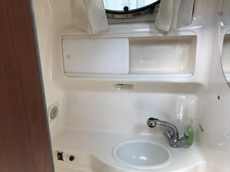 Slide: The Image of 2002 Chaparral Signature 300 bathroom sink area with storage and porthole window. - 33