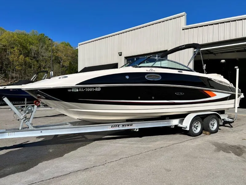 The Image of 2013 Sea Ray 260 Sundeck boat on a trailer outside a warehouse. - 1