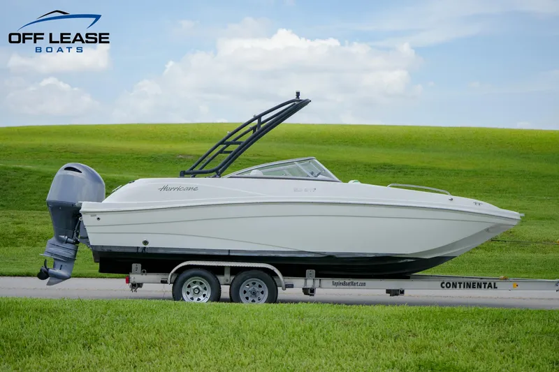 Slide: The Image of 2020 Hurricane 217 SD boat on trailer, side view, green field background. - 1