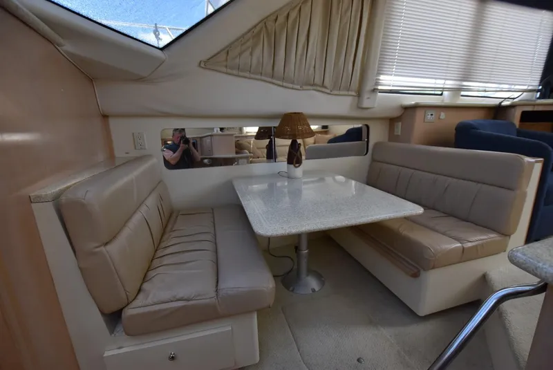 Slide: The Image of 1999 Carver 356 Aft Cabin interior dining area with beige seating and table. - 11