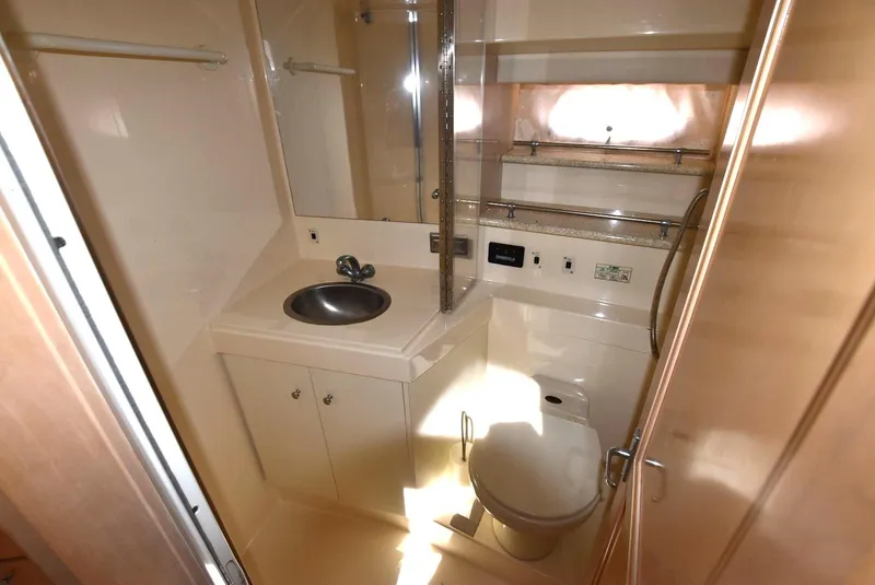 Slide: The Image of 1999 Carver 356 Aft Cabin bathroom with sink, toilet, and storage shelves. - 17