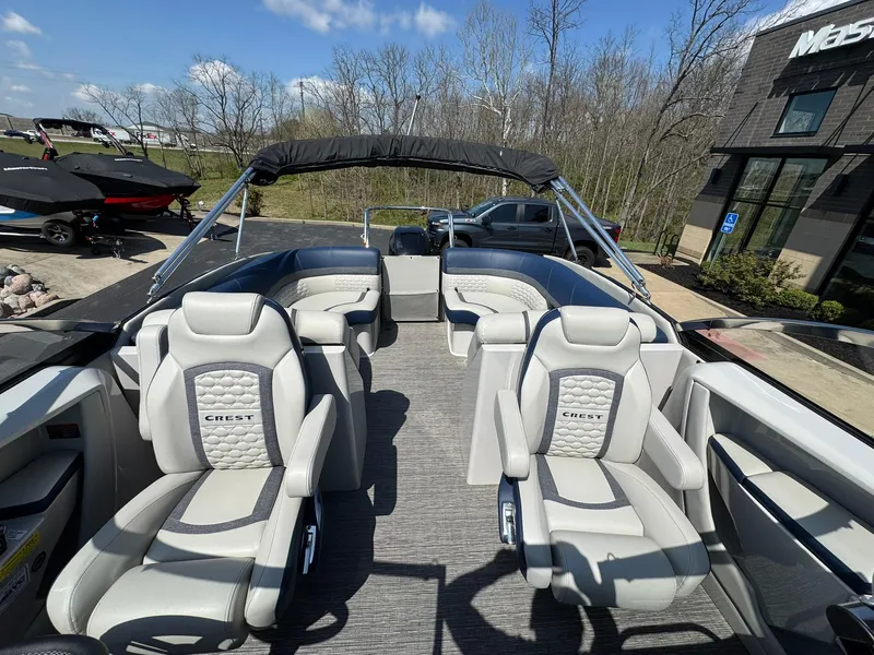 Slide: The Image of 2023 Crest Continental 250 boat with luxurious seating, parked outdoors under a clear blue sky. - 10