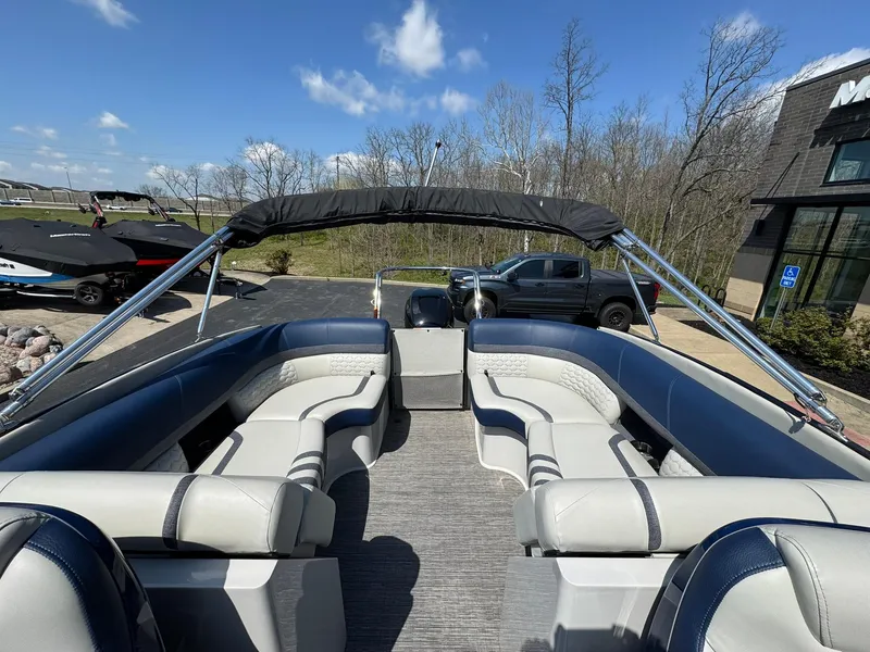 Slide: The Image of 2023 Crest Continental 250 pontoon boat with spacious seating, parked outdoors under a clear sky. - 11