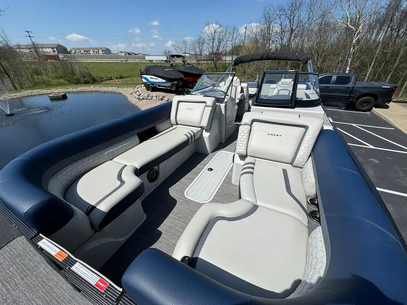 Slide: The Image of 2023 Crest Continental 250 boat with luxurious seating, parked near a pond under a clear sky. - 6