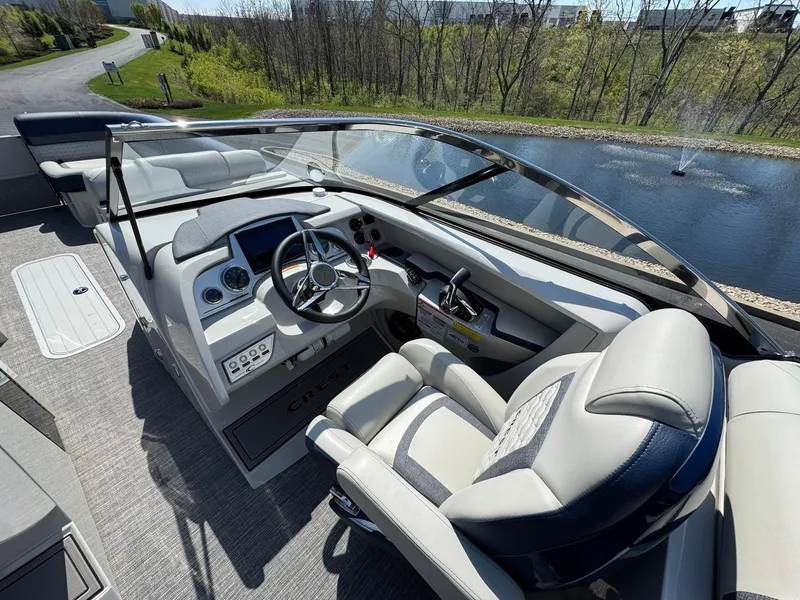 Slide: The Image of 2023 Crest Continental 250 boat interior with steering wheel and seating, near a scenic lake. - 8