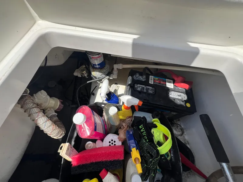 Slide: The Image of Storage compartment of a 2009 Everglades 210CC boat with various cleaning supplies and a battery. - 16