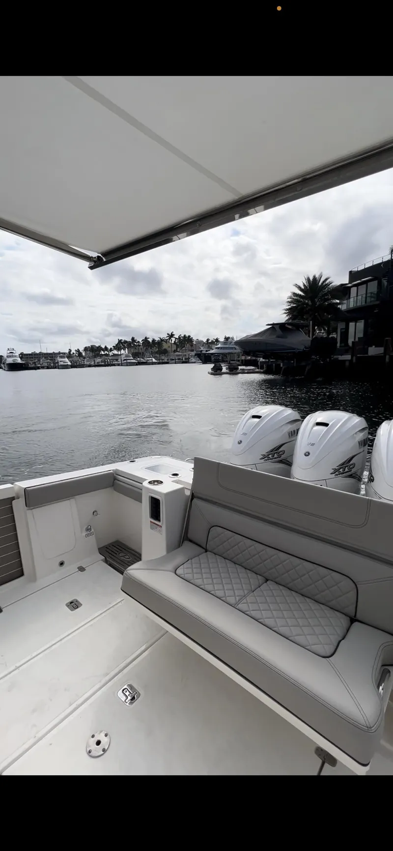 Slide: The Image of 2022 Pursuit S 428 Sport boat with twin outboard engines on a calm waterfront. - 11