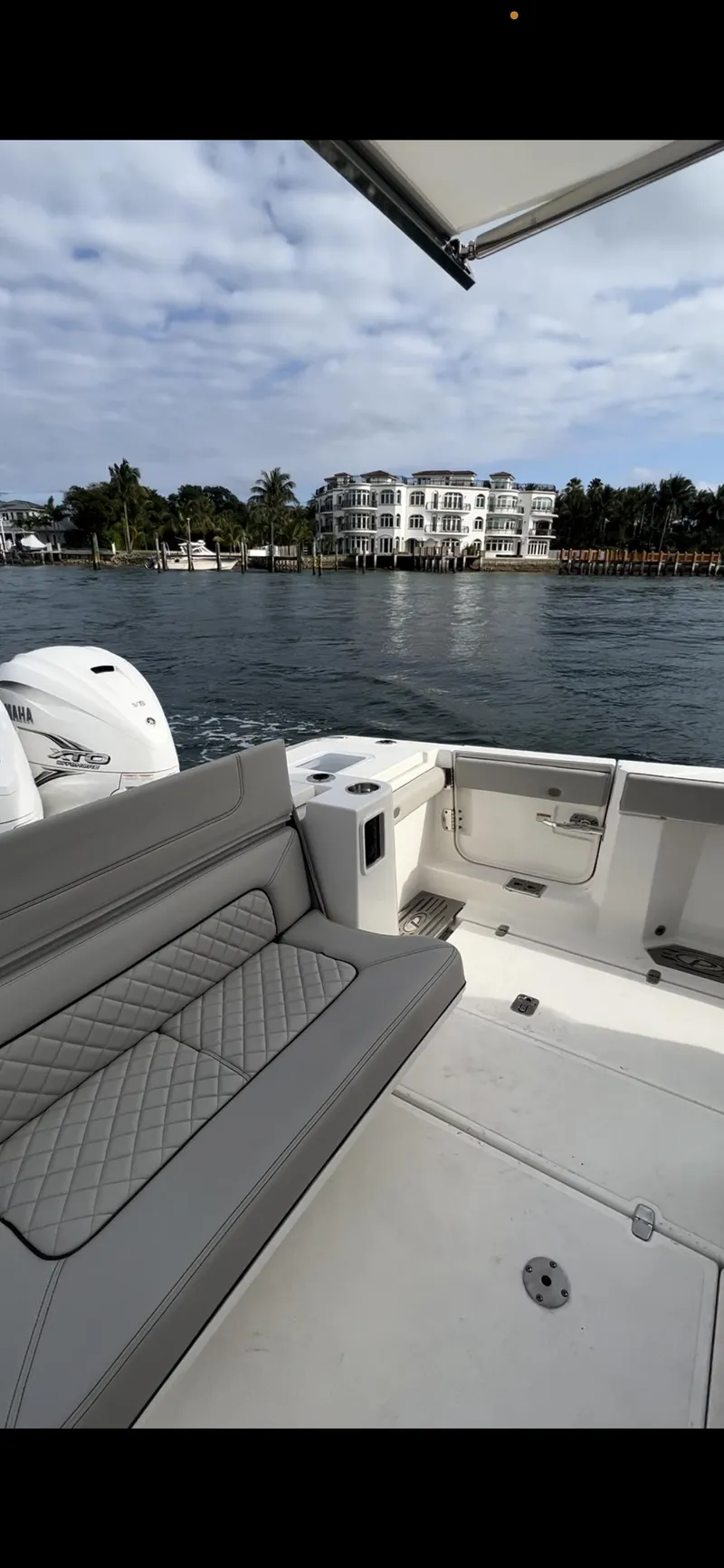 Slide: The Image of 2022 Pursuit S 428 Sport boat with luxurious seating, docked near waterfront properties. - 9