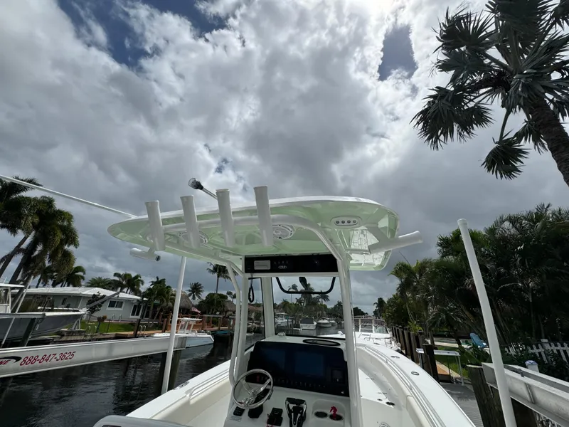 Slide: The Image of 2022 Sea Hunt 27 Gamefish boat docked under cloudy sky with palm trees. - 7