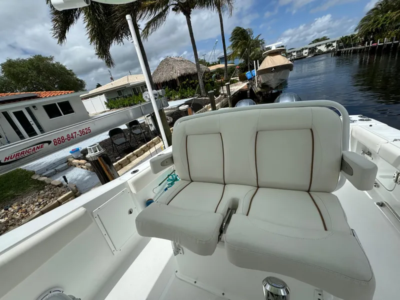 Slide: The Image of 2022 Sea Hunt 27 Gamefish boat with white cushioned seating, docked near waterfront homes. - 9