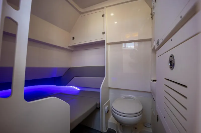 Slide: The Image of 2022 Scout 330 LXF boat interior with modern bathroom and cozy sleeping area. - 13