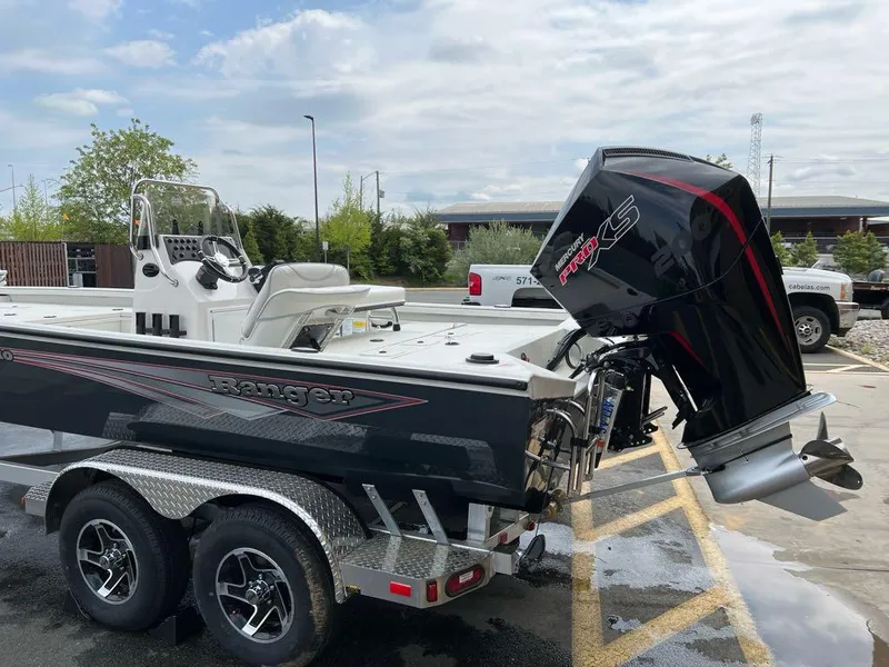 The Image of 2024 Ranger RB210 boat with powerful outboard motor, parked on a trailer in a lot. - 0