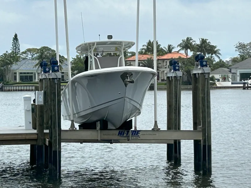 Slide: The Image of 2023 Sailfish 290 CC boat docked on a lift in a marina. - 1
