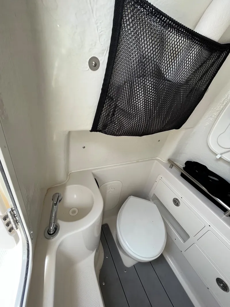 Slide: The Image of 2023 Sailfish 290 CC boat interior bathroom with sink and toilet. - 11