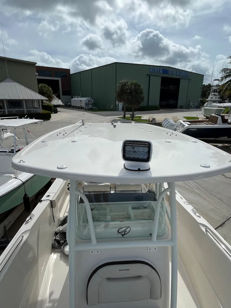 Slide: The Image of 2023 Sailfish 290 CC boat docked near a marina under a cloudy sky. - 15
