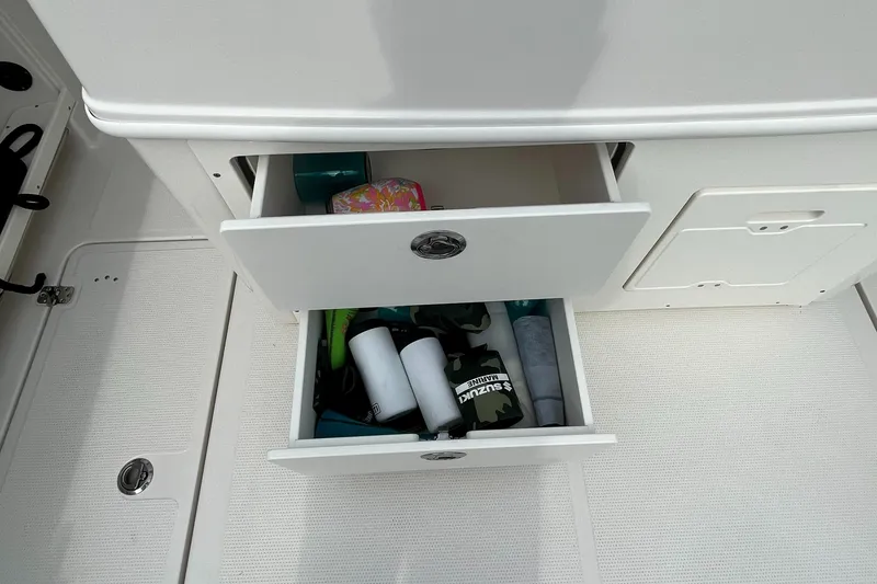Slide: The Image of Storage drawers on the 2023 Sailfish 290 CC boat, filled with various items. - 21