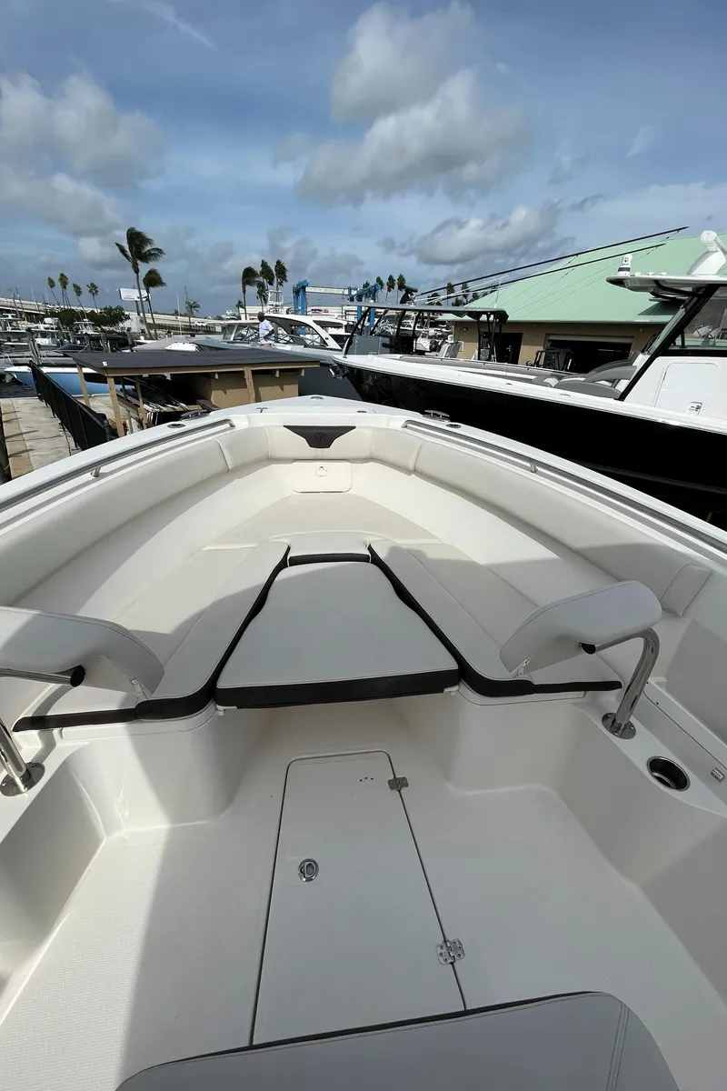 Slide: The Image of 2023 Sailfish 290 CC boat with spacious deck and seating at a marina. - 27