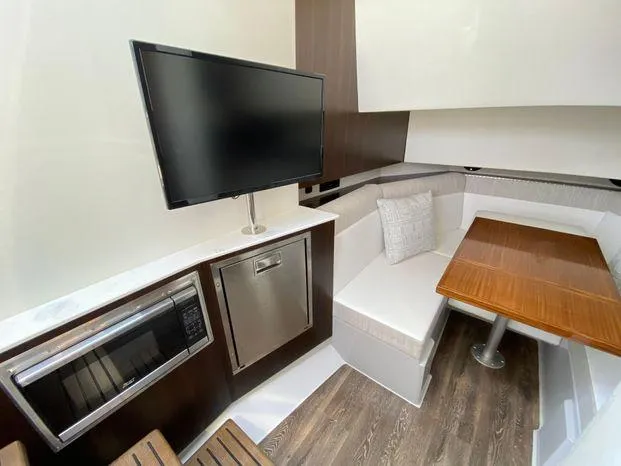 Slide: The Image of 2023 Cruisers Yachts 38 GLS OB interior with TV, microwave, and dining area. - 10