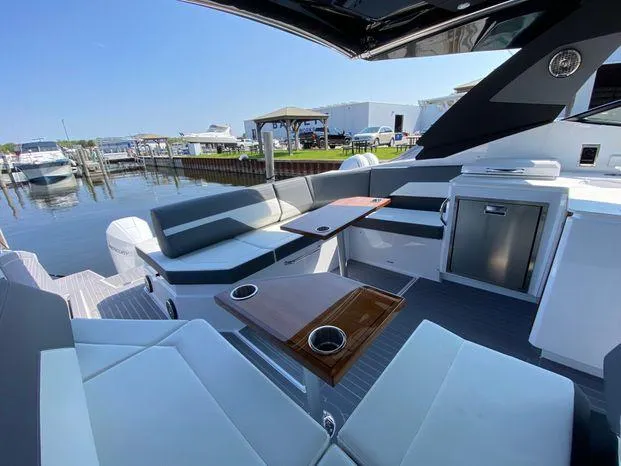 Slide: The Image of 2023 Cruisers Yachts 38 GLS OB interior with seating and tables at a marina. - 15