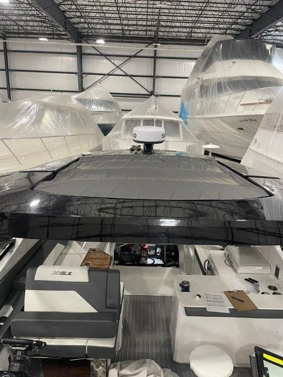 Slide: The Image of 2023 Cruisers Yachts 38 GLS OB in a storage facility, surrounded by other boats. - 38