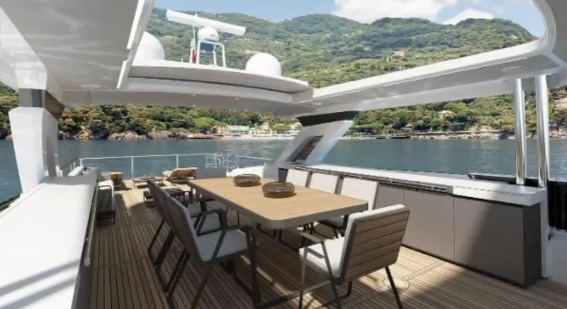 Slide: The Image of Luxurious 2025 Absolute NAVETTA 75 yacht deck with dining area, scenic coastal backdrop. - 7